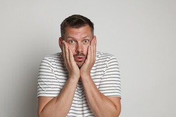 Man suffering from panic attack on light grey background