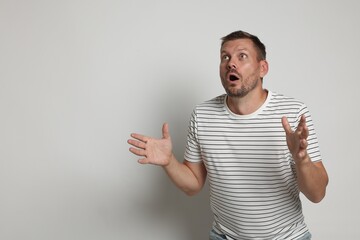 Man suffering from panic attack on light grey background, space for text
