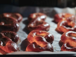 Freshly baked Mucenici rest on a baking sheet, their figure-eight shapes gleaming warmly. These...