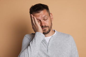 Man suffering from hangover on beige background
