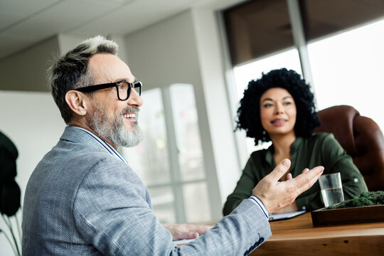 Professional business discussion between mature man and young woman in a modern office setting