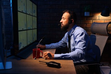 Security guard monitoring CCTV cameras in office at night