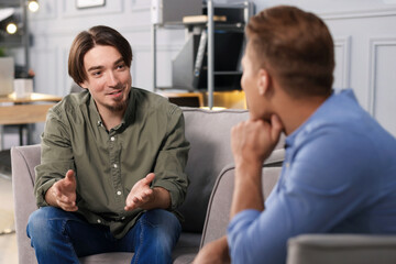 Colleagues having conversation during break in armchairs at office