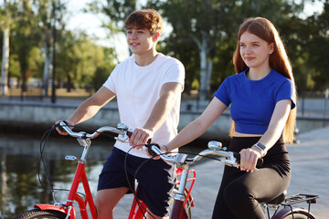 Obraz premium Teenage girl and boy riding bicycles on city street
