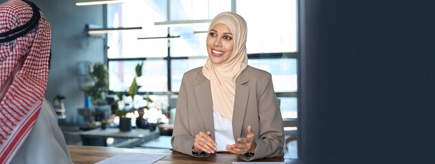 Middle eastern arab businesswoman communicating with business partner, giving consultation. Young...