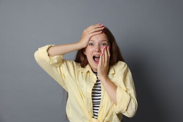 Teenage girl suffering from panic attack on grey background