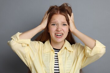 Teenage girl suffering from panic attack on grey background