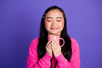 Young Woman in Pink Sweater Holding a Mug Relaxing on a Purple Background
