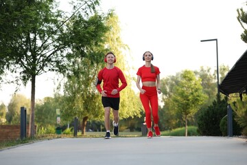 Fototapeta premium Happy couple in headphones running outdoors, low angle view. Morning exercise