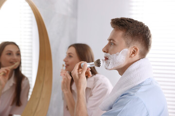 Young couple getting ready together near mirror at home