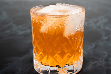 A vibrant cocktail sits in a beautifully crafted crystal glass filled with ice. The drink's...
