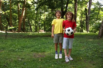 Obraz premium Cute little kids with soccer ball in park, space for text