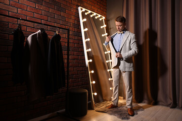Handsome man getting ready near mirror indoors