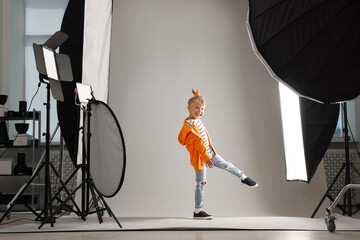 Little boy on light grey background in photo studio with professional equipment