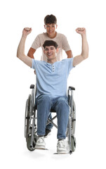 Happy young man in wheelchair and caregiver on white background