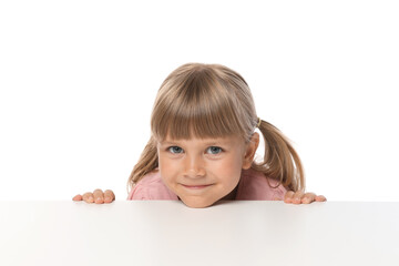 Curious little girl peeking over table against white background