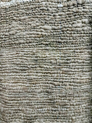Hand-woven cotton in gray-brown tones, with a dense and coarse texture from natural yarn.