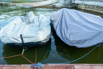 A covered boat at the pier longing for the sun and the thrill of adventure on the water. Boat...
