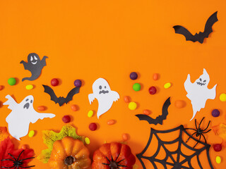 Small pumpkins, ghosts, bats and candies on an orange background will create a festive mood for...