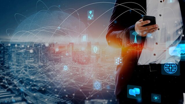 A businessman stands in a suit, using a smartphone against a vibrant city skyline, surrounded by digital icons representing modern technology and connectivity. Xenic
