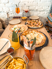 Colorful assortment of delicious food and drinks on a wooden table in a cozy restaurant, showcasing...