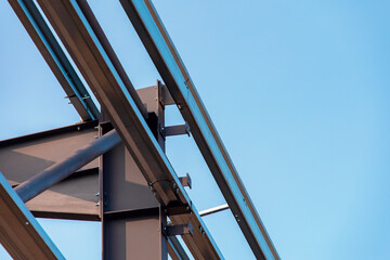 Close-up of steel frame structure elements and connection points against blue sky