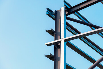 Close-up of steel frame structure elements and connection points against blue sky