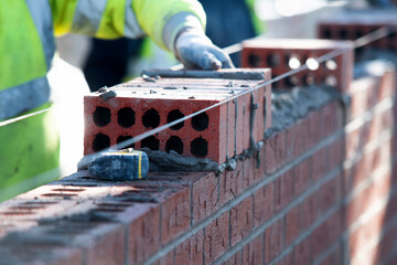 Close-up of skilled bricklayer working on construction site laying bricks for wall construction