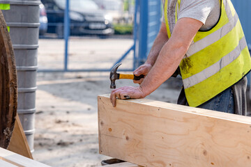 Close-up of hands of builder joiner using plywood and timber to asseble shutter panel for concrete...