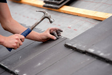 Construction worker carefully installing roofing materials on newly built residential structure...