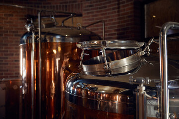 A long row of copper tanks is neatly lined up against a brick wall
