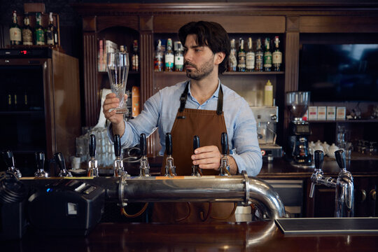 Brewer man brewer is carefully pouring beer into a glass