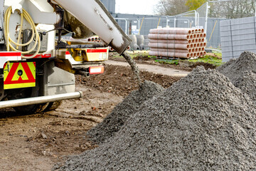 Semy-dry ready mix concrete delivered on construction site and unloaded into pile on ground