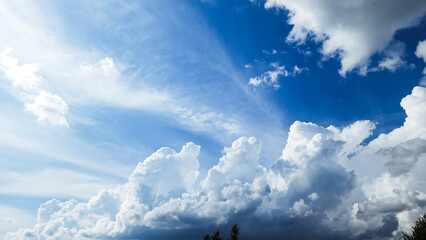 A stunning view of a bright blue sky with fluffy clouds over lush green trees and majestic...