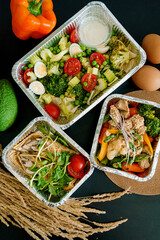 Takeaway healthy food in aluminum foil containers with vegetables and grains.