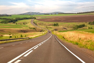 Asphalt country road among fields and picturesque nature