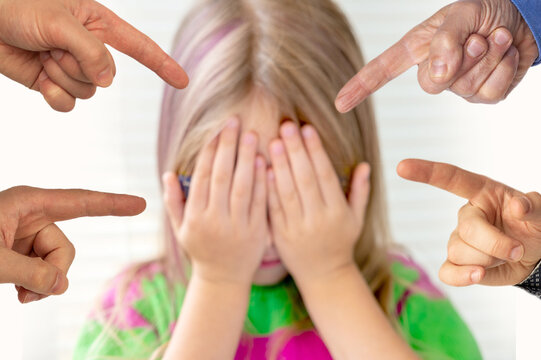 Bullying and social conflict, person being singled out, representing themes exclusion, child covers their face with hands as multiple fingers point towards them, peer pressure, and harassment