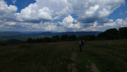 A stunning view of a lush mountain range under a bright blue sky with rolling clouds, perfect for travel, nature, and outdoor adventure promotions