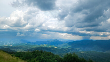Obraz premium A stunning view of a lush mountain range under a bright blue sky with rolling clouds, perfect for travel, nature, and outdoor adventure promotions