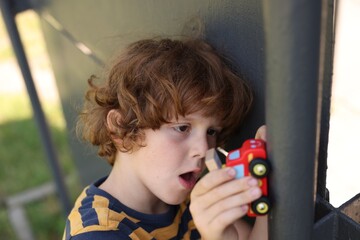 Little boy playing with toy car outdoors