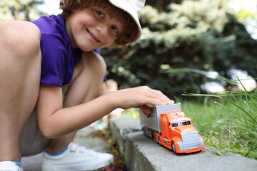 Little boy playing with toy car outdoors, selective focus
