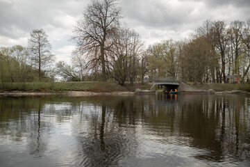 Kayakers Paddling Under a Historic Stone Bridge on a Calm River Surrounded by Lush Trees During an...