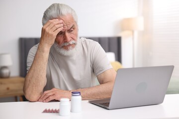 Senior man having online consultation with doctor via laptop at table indoors
