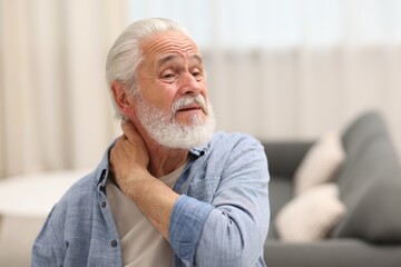 Senior man suffering from neck pain at home