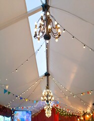 Elegant Chandeliers and Festive String Lights Decorate Interior White Tent for Event