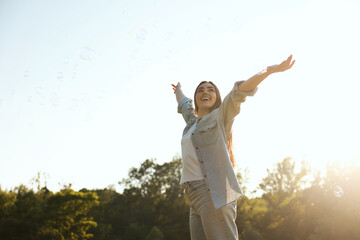 Feeling freedom. Happy young woman enjoying time in nature on sunny day, low angle view. Space for text