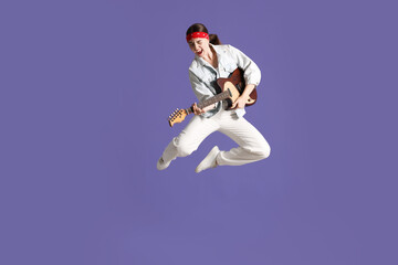 Woman with guitar jumping on purple background