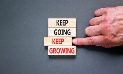 Keep going and growing symbol. Concept words phrase Keep going keep growing on beautiful wooden blocks. Beautiful grey background. Businessman's hand. Business Keep going growing concept. Copy space.