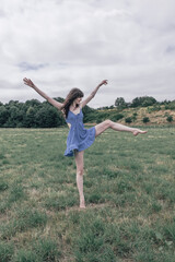 A young woman with voluminous curly brown hair, wearing a sleeveless ruffled blue summer dress,...