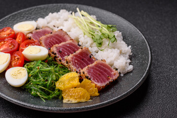 Seafood bowl, tuna tataki fillet slices with rice, oranges, tomatoes and sauce. Tuna bowl